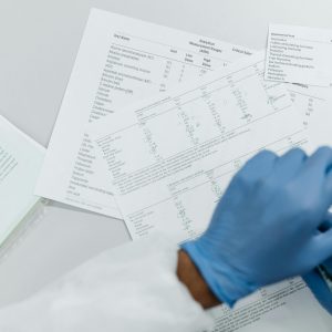 Close-up of gloved hands reviewing printed lab test results on a white surface.